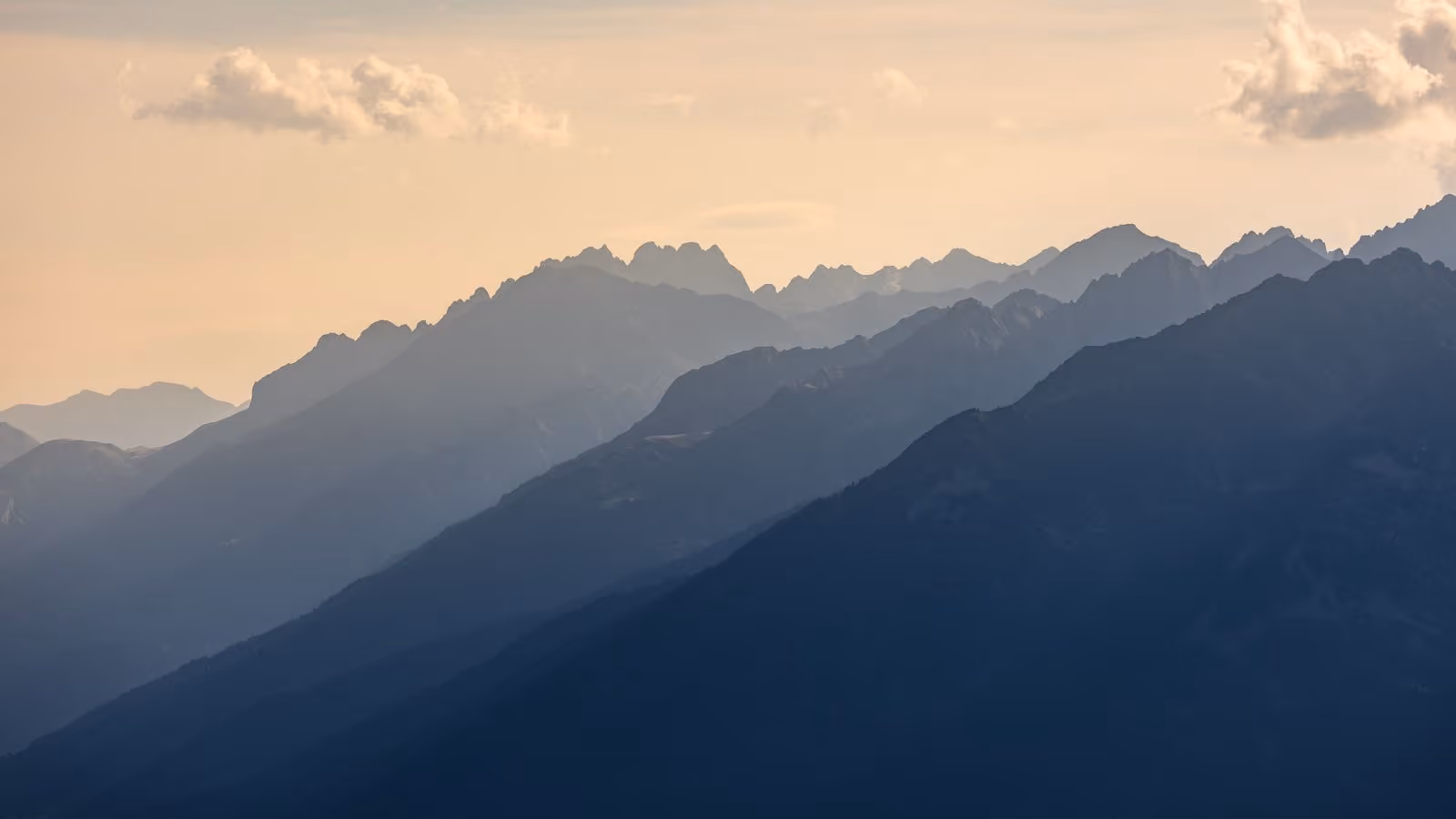 Mountain ridges receding in layers through haze, each one paler than the ridge in front of it.