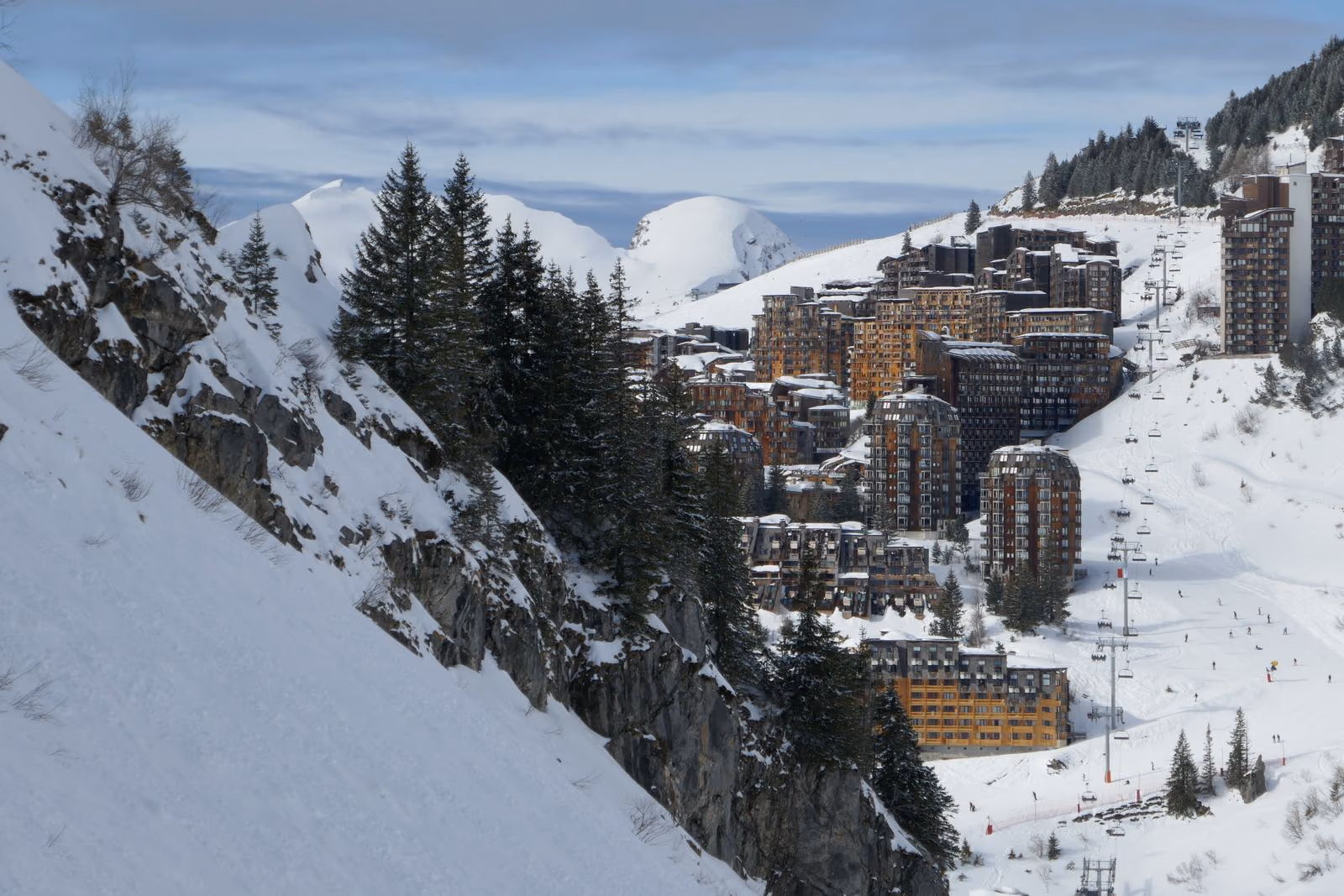 Une station de ski entourée de montagnes enneigées et de forêts.
